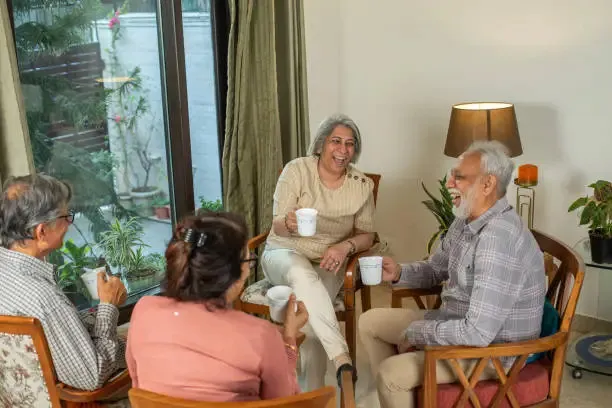 A group of elderly residents at Ashirwad Elders Home engaging in a joyful conversation during a community event.